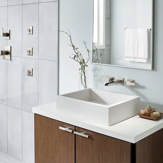 Modern bathroom with Delta Ara wall mount faucet in Brilliance Stainless finish above rectangular white vessel sink on white counter top. Rectangular mirror above and delta shower to the left.