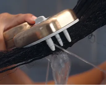 Delta Versacurl detangling shower tool in champagne bronze being pulled through dark curly hair held up by woman&rsquo;s hand.