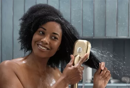 Woman with curly hair detangling her hair in the shower