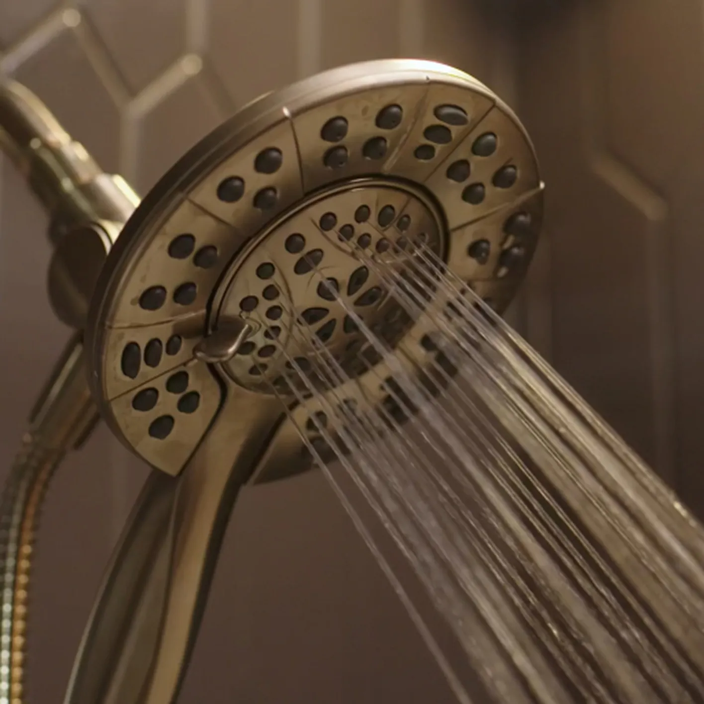 Close up of Delta In2ition 2-in-1 shower head in champagne bronze pouring water. 
