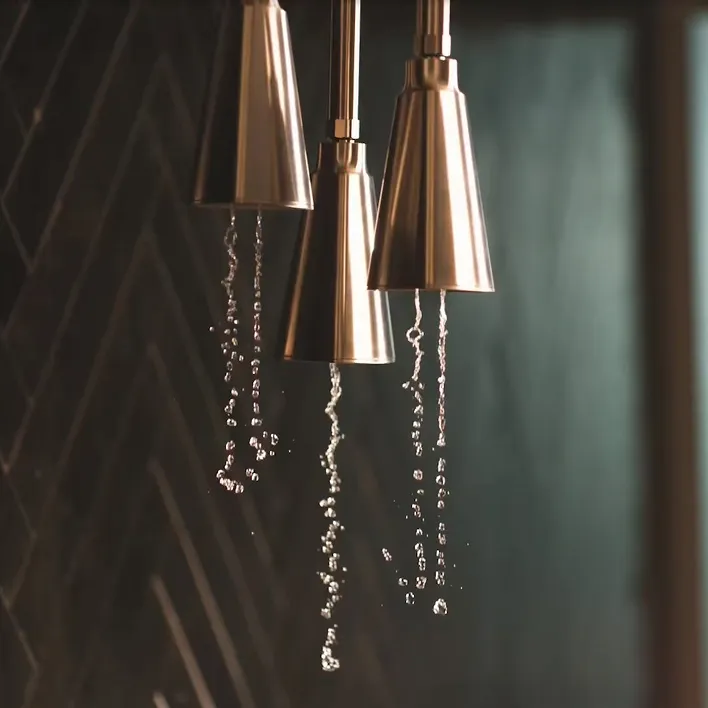 Delta rain shower head in champagne bronze pouring water. 
