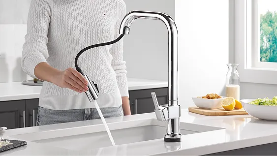 Woman in white sweater uses pull-down spray nozzle from Delta single-handle chrome kitchen faucet.
