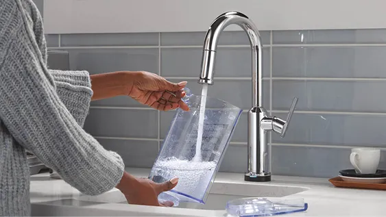 Woman fills water jug from Delta single-handle kitchen faucet in chrome.