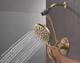 Hand holding champagne bronze Delta SureDock hand shower while it runs.