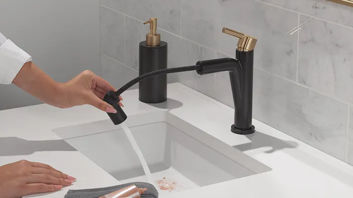 Single handle Delta Nicoli pull-down bathroom faucet in matte black with champagne bronze handle.