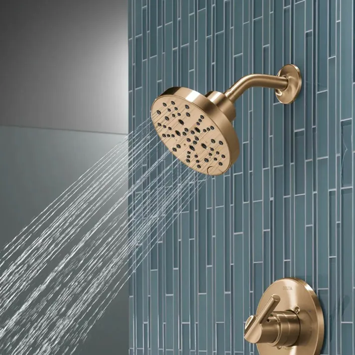 Champagne bronze Delta shower head and valve handle working with green tile.