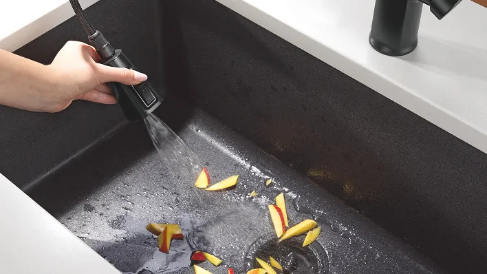 Delta ProClean spray nozzle from pull-down matte black sink faucet sprays tangerine pieces in Delta granite undermount kitchen sink.