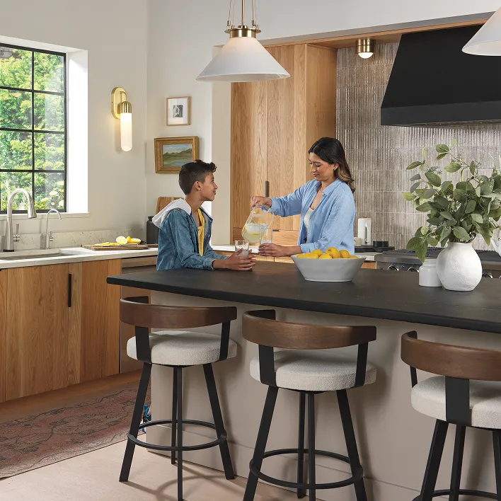 Mother and son enjoy lemonade at kitchen island with chrome Delta faucets in background.