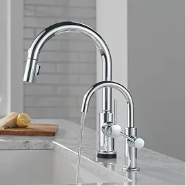 Delta Beverage Faucet in Chrome pouring water into a sink next to Delta Tall/High Arc Single Handle Contemporary Kitchen faucet.
