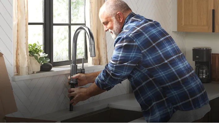 Man installs Delta Trinsic Single Handle Pull-Down Kitchen Faucet with Touch2O Technology in Arctic Stainless.