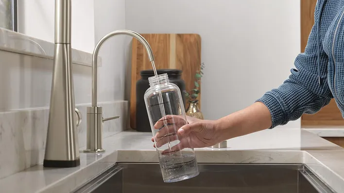 Hand fills water bottle from Delta Contemporary Beverage Faucet in Stainless.